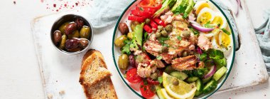 Tuna salad with boiled egg, tomato, lettuce, cucumber and red onion. Healthy and detox food concept. Ketogenic diet. Fresh vegetable salad bowl on white background. Top view. Panorama, banner.