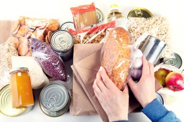 Food donations with pasta, rice, oil, peanut butter, canned food, jam and other  on light background, top view.  Food donations or delivery concept.
