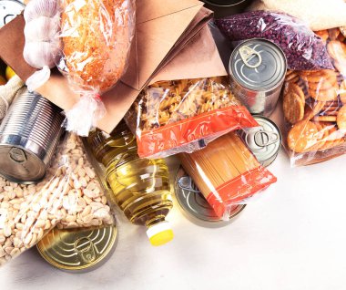 Food donations with pasta, rice, oil, peanut butter, canned food, jam and other  on light background, top view with copy space. Food donations or delivery concept.