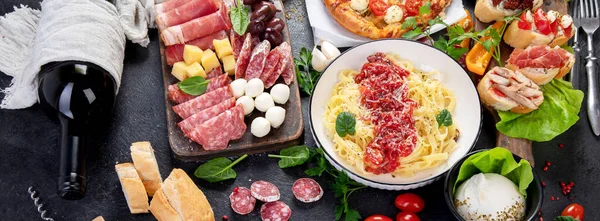 Italian food dishes on dark background. Traditional italian cuisine  concept. Dishes and appetizers of indeed cuisine. Mideterranean diet food high in vitamin and antioxidants. Top view,banner