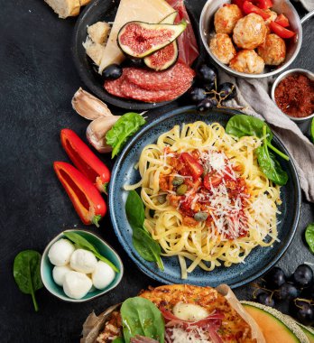 Dinner table of italian meals dishes.  Pizza, pasta, antipasto  on black background. Healthy eating concept. Top view