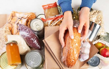 Food donations with pasta, rice, oil, peanut butter, canned food, jam and other  on light background, top view with copy space. Food donations or delivery concept.