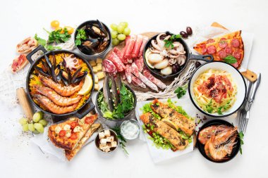 Assortment various Mediterranean food - fish, octopus, shrimp,  seafood, mussels, sauces, pasta, pizza on a white background. Top view.