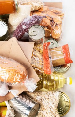 Food donations with pasta, rice, oil, peanut butter, canned food, jam and other  on light background, top view with copy space. Food donations or delivery concept.
