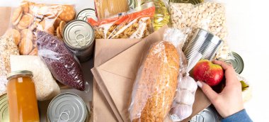 Food donations with pasta, rice, oil, peanut butter, canned food, jam and other  on light background, top view. Food donations or delivery concept.