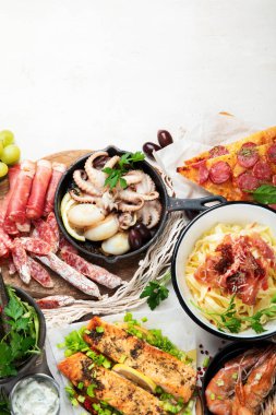 Assortment various Mediterranean food - fish, octopus, shrimp,  seafood, mussels, sauces, pasta, pizza on a white background. Top view.