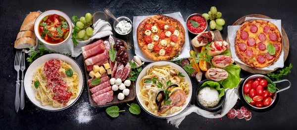 Italian food dishes on dark background. Traditional italian cuisine  concept. Dishes and appetizers of indeed cuisine. Mideterranean diet food high in vitamin and antioxidants. Top view, banner