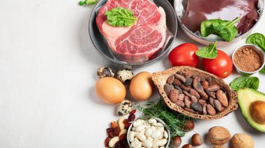 Doğal demir içeren yiyecek. Fe: Karaciğer, avokado, brokoli, ıspanak, maydanoz, fasulye, fındık, beyaz arka planda. Üst Manzara. Boşluğu kopyala.