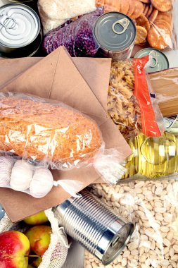 Food donations with pasta, rice, oil, peanut butter, canned food, jam and other  on light background, top view. Food donations or delivery concept.