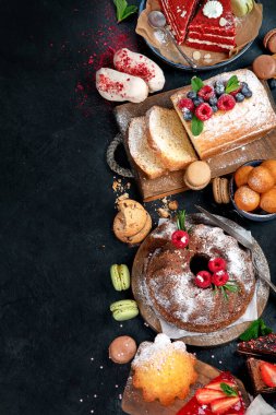 Koyu arkaplanda farklı tatlılar. Pastalı, çikolatalı ve kırmızı kadife kekli lezzetli tatlı masası. Tatil tatlısı yeme konsepti. Üst görünüm, alanı kopyala