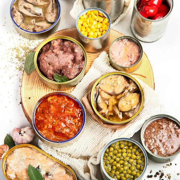 Various canned vegetables, meat, fish and fruits in tin cans. On a white background. Top view.