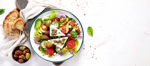 希腊沙拉 新鲜黄瓜 西红柿 红洋葱 羊乳酪和橄榄与橄榄油的白色背景 健康食品 高瞻远瞩 具有复制空间的全景 — 图库照片