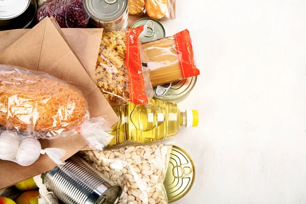 Food donations with pasta, rice, oil, peanut butter, canned food, jam and other  on light background, top view with copy space. Food donations or delivery concept.