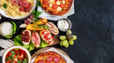 Italian food dishes on dark background. Traditional italian cuisine  concept. Dishes and appetizers of indeed cuisine. Mideterranean diet food high in vitamin and antioxidants. Top view, copy space