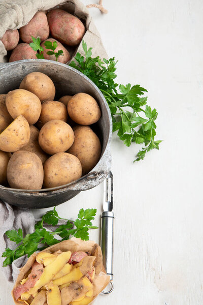 Raw potato food. Fresh potatoes in an old cooking pot on a white background. Top view. Copy space.