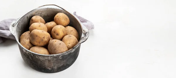 生のジャガイモ料理 白い背景に古い調理鍋で新鮮なジャガイモ 最上階だ コピースペース付きパノラマ — ストック写真