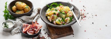 Beyaz arka planda pastırmalı bir kase sıcak patates salatası. Üst Manzara. Kopyalama alanı olan Panorama.