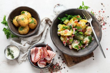 Beyaz arka planda pastırmalı bir kase sıcak patates salatası. Üst görünüm.