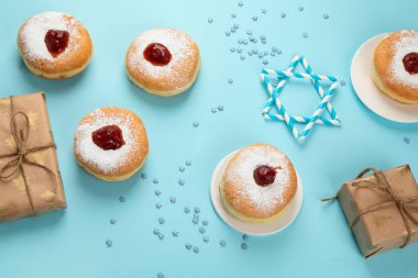 Hanuka tatlı donutları sufganiyot (geleneksel çörekler), meyveli reçel ve mavi kağıtta beyaz mumlar. Yahudi bayramı Hanuka konsepti.