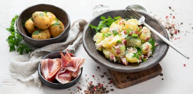 Beyaz arka planda pastırmalı bir kase sıcak patates salatası. Üst görünüm.