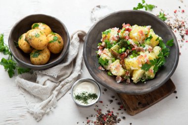 Beyaz arka planda pastırmalı bir kase sıcak patates salatası. Üst görünüm.