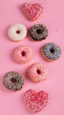 Çikolatalı donut, marşmelov ve pembe arka planda şeker serpiştirme, üst manzara. Renkli karnaval ya da doğum günü partisi kartı. Ulusal Çörek Gününüz kutlu olsun..