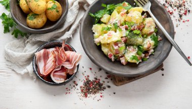 Beyaz arka planda pastırmalı bir kase sıcak patates salatası. Üst görünüm.