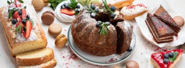 Çeşit çeşit kek, kek, tatlı, beyaz arka planda meyve soslu kurabiye içeren tatlı masası. Üst Manzara. Panorama.