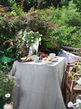 Bahçe masasında Avrupalı kahvaltısı. Taşra yaşam tarzı ya da hafta sonu sabah konsepti. Huzurlu kırsal manzara.