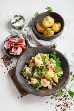 Beyaz arka planda pastırmalı bir kase sıcak patates salatası. Üst görünüm.