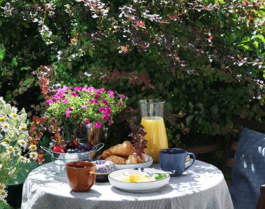 Bahçe masasında Avrupalı kahvaltısı. Taşra yaşam tarzı ya da hafta sonu sabah konsepti. Huzurlu kırsal manzara.