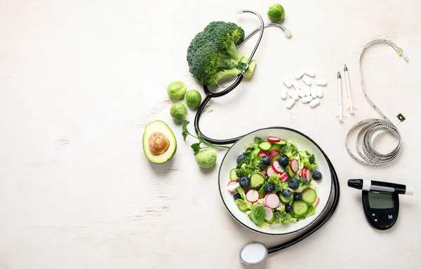 Top view of healthy food in plate with stethoscope, cholesterol diet and diabetes control on white background. World health day and medical concept. Copy space.