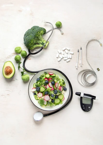 Top view of healthy food in plate with stethoscope, cholesterol diet and diabetes control on white background. World health day and medical concept.
