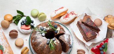 Çeşit çeşit kek, kek, tatlı, beyaz arka planda meyve soslu kurabiye içeren tatlı masası. Üst Manzara. Kopyalama alanı olan Panorama.