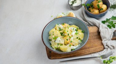 Beyaz arka planda bir tabakta patates, yumurta, yeşil soğan ve mayonez salatası. Kopyalama alanı olan Panorama