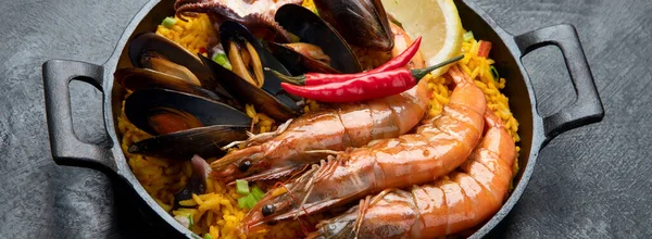 经典的西班牙菜 海鲜海鲜饭在传统的平底锅上的深色背景 顶视图 西班牙海鲜 上面有虾仁 青豆和新鲜柠檬片 — 图库照片