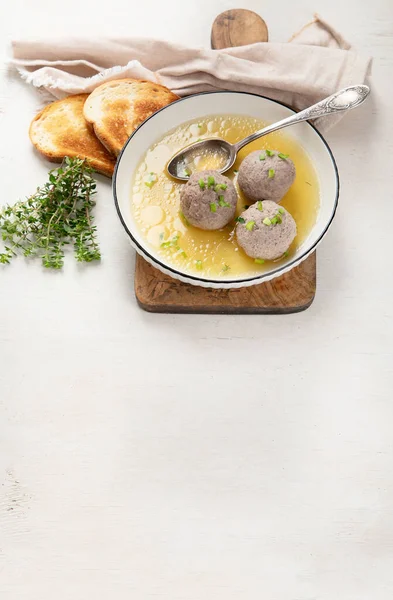 Canederli or Knodel in broth with green onion, typical pasta or dumplings for Alps, Alto Adige, German, Italian, Austrian cuisine. Made from stale bread, milk, eggs, speck. White background. Top view. Copy space.