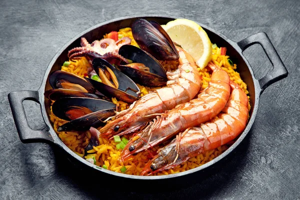 经典的西班牙菜 海鲜海鲜饭在传统的平底锅上的深色背景 顶视图 西班牙海鲜 上面有虾仁 绿豆和新鲜柠檬片 — 图库照片
