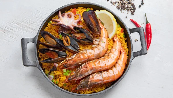 经典的西班牙菜 海鲜海鲜饭放在传统的平底锅上 顶部观景 西班牙海鲜 上面有虾仁 绿豆和新鲜柠檬片 — 图库照片