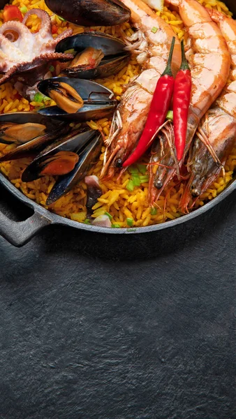 经典的西班牙菜 海鲜海鲜饭在传统的平底锅上的深色背景 顶视图 西班牙海鲜 上面有虾仁 绿豆和新鲜柠檬片 — 图库照片