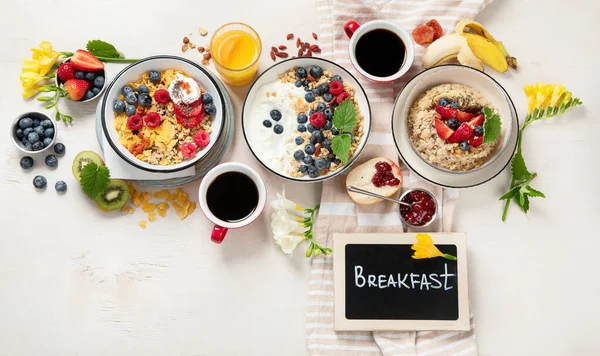 stock image Breakfast food table. Healthy breakfast or brunch set, meal variety with granola, porridge, cornflakes, fresh berries, fruits and various of topping on a white background. Top view.