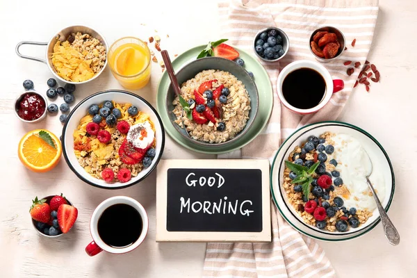 stock image Breakfast food table. Healthy breakfast or brunch set, meal variety with granola, porridge, cornflakes, fresh berries, fruits and various of topping on a white background. Top view.