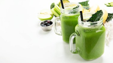 Beyaz arka planda kavanoz bardakta sağlıklı yeşil meyve püresi. Boşluğu kopyala