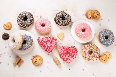 Donut deseni. Çeşit çeşit jöleli donutların üst görüntüsü. Kremalı renkli çörekler. Açık arkaplana serpiştirilmiş çeşitli renkli donutlar..