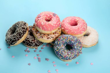 Donut deseni. Çeşit çeşit jöleli donutların üst görüntüsü. Kremalı renkli çörekler. Açık arkaplana serpiştirilmiş çeşitli renkli donutlar..