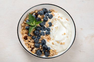 Sağlıklı kahvaltı için yoğurt ve böğürtlenli granola. Beyaz arka planda, yaban mersini ve ahududu aromalı bir kase Yunan yoğurdu..