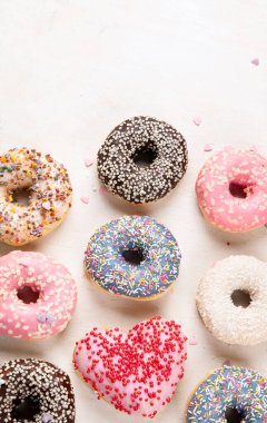 Donut deseni. Çeşit çeşit jöleli donutların üst görüntüsü. Kremalı renkli çörekler. Açık arkaplan üzerine serpiştirilmiş çeşitli renkli donutlar. Boşluğu kopyala.