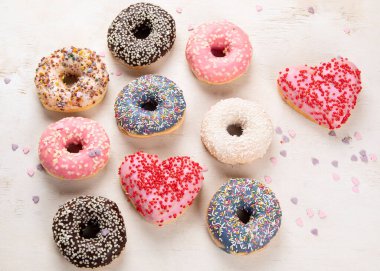 Donut deseni. Çeşit çeşit jöleli donutların üst görüntüsü. Kremalı renkli çörekler. Açık arkaplana serpiştirilmiş çeşitli renkli donutlar..