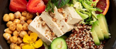 Sağlıklı vejetaryen yemek kasesi. Avokado, kinoa, salatalık, kırmızı portakal, nohut, peynir, salata ve beyaz arka planda çilek. Üst görünüm.