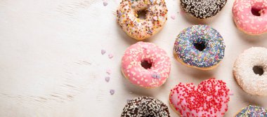 Donut deseni. Çeşit çeşit jöleli donutların üst görüntüsü. Kremalı renkli çörekler. Açık arkaplan üzerine serpiştirilmiş çeşitli renkli donutlar. Kopyalama alanı olan Panorama.